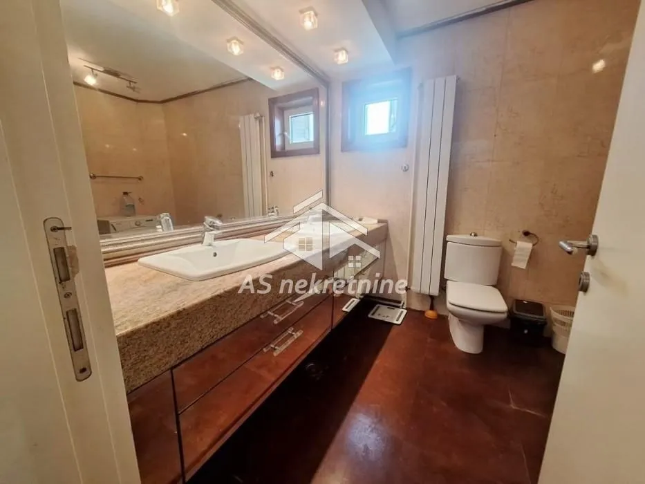 Bathroom with washbasin, large mirror, and toilet.