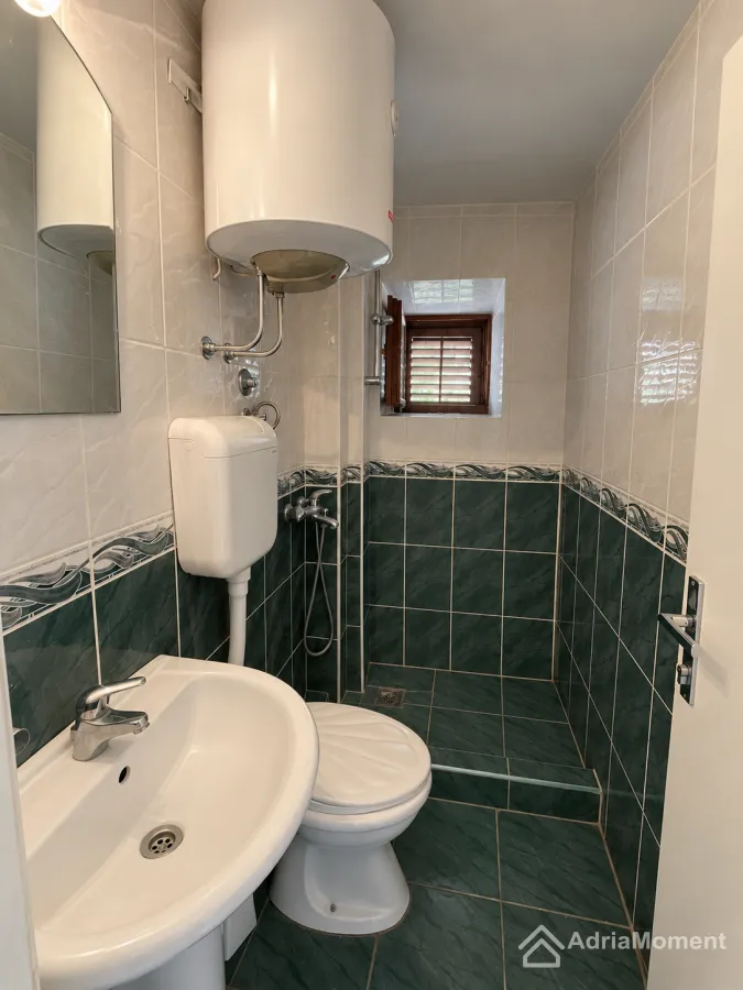 Manje kupatilo sa lavaboom, wc šoljom, tuš kabinom i bojlerom.