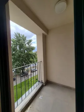 Prazan natkriveni balkon sa metalnom ogradom i pogledom na ulicu i drveće. - image 12
