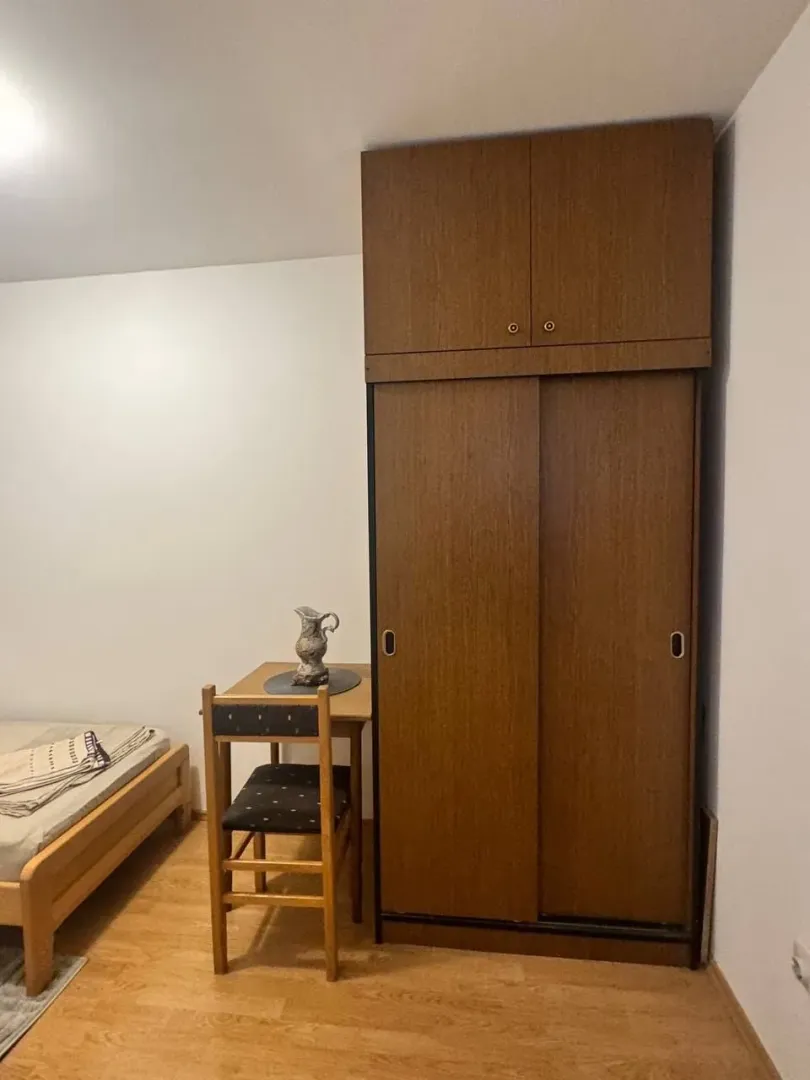 Furnished bedroom with a wooden bed, wardrobe, and a desk with a chair.