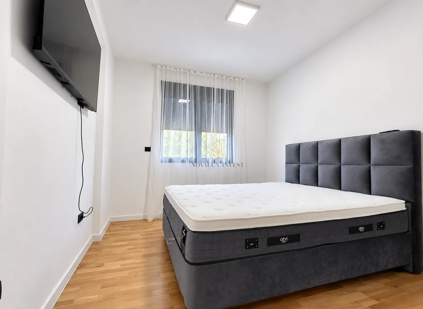 Bedroom with a large double bed and a wall-mounted TV.