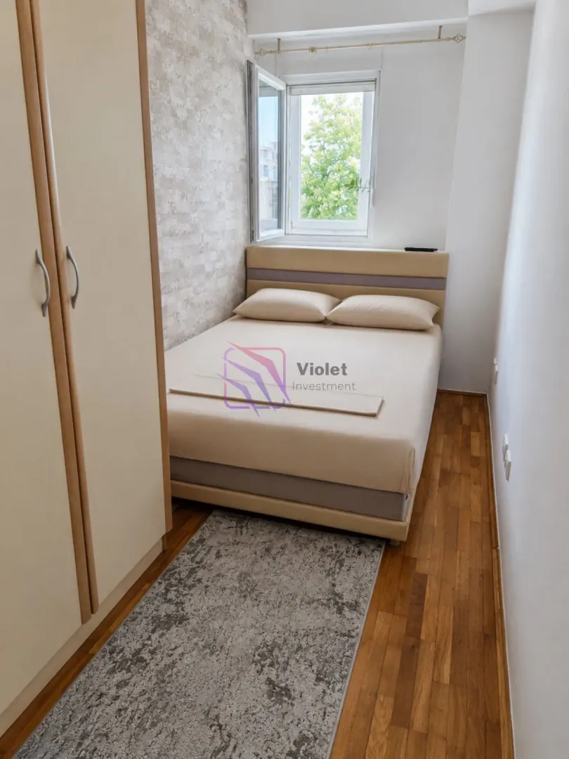 Manja spavaća soba sa bračnim krevetom, garderoberom i prozorom.