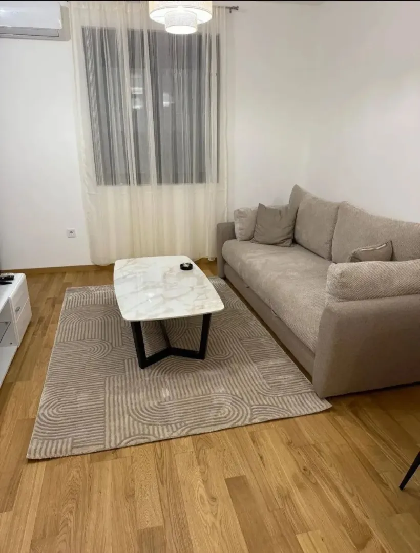 Dnevna soba sa garniturom, stočićem i parketom na podu.