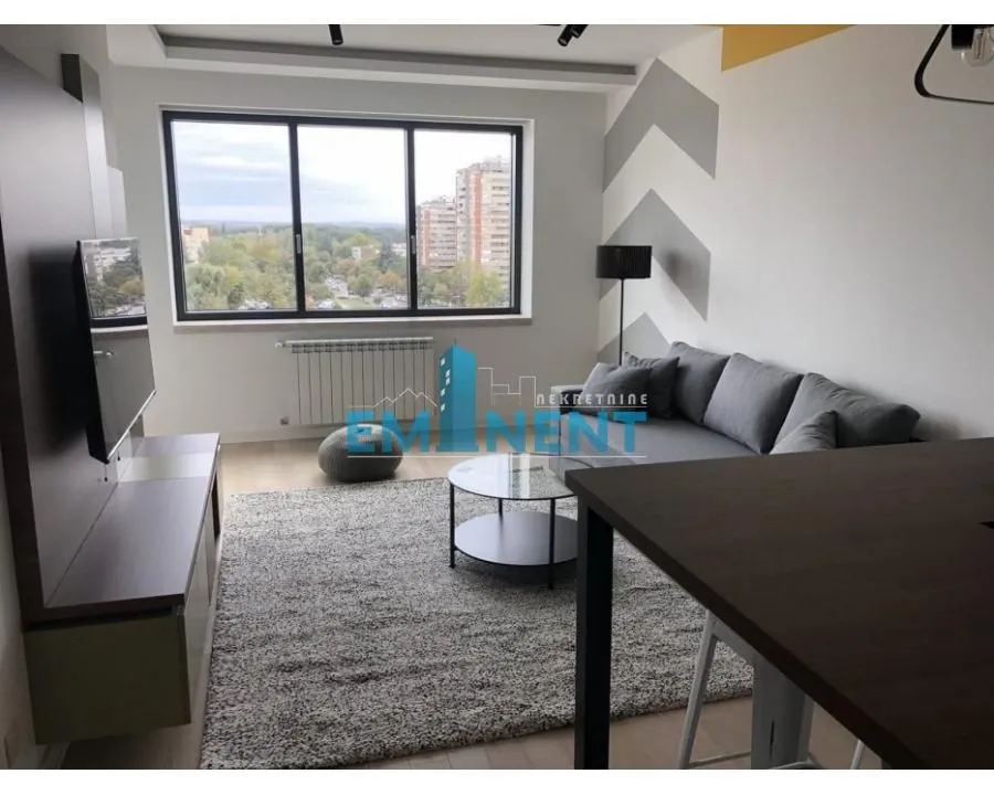 Living room with a sofa, TV unit, and a window with a city view.