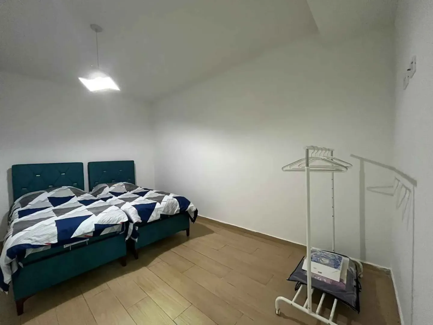 Spavaća soba sa dva kreveta i stalkom za odjeću.
