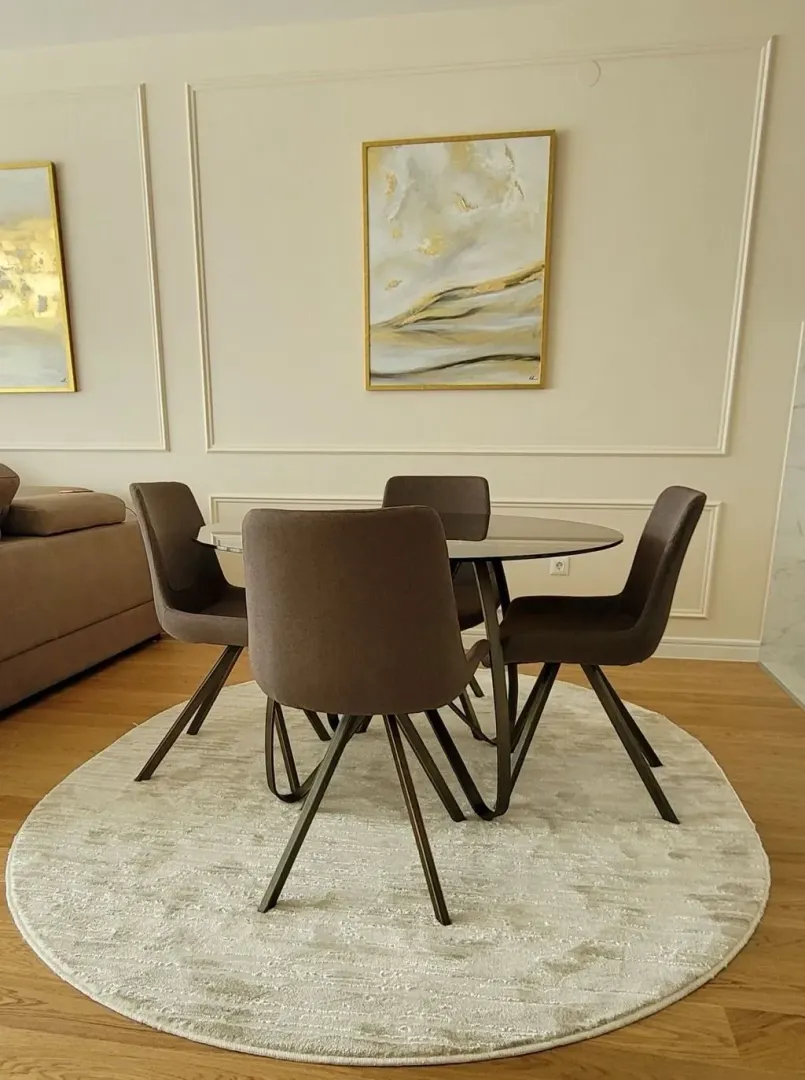 Dining table with four chairs on a light rug in the living room.