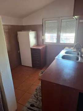 View of a small kitchen with a sink, countertops, and a refrigerator. - image 2