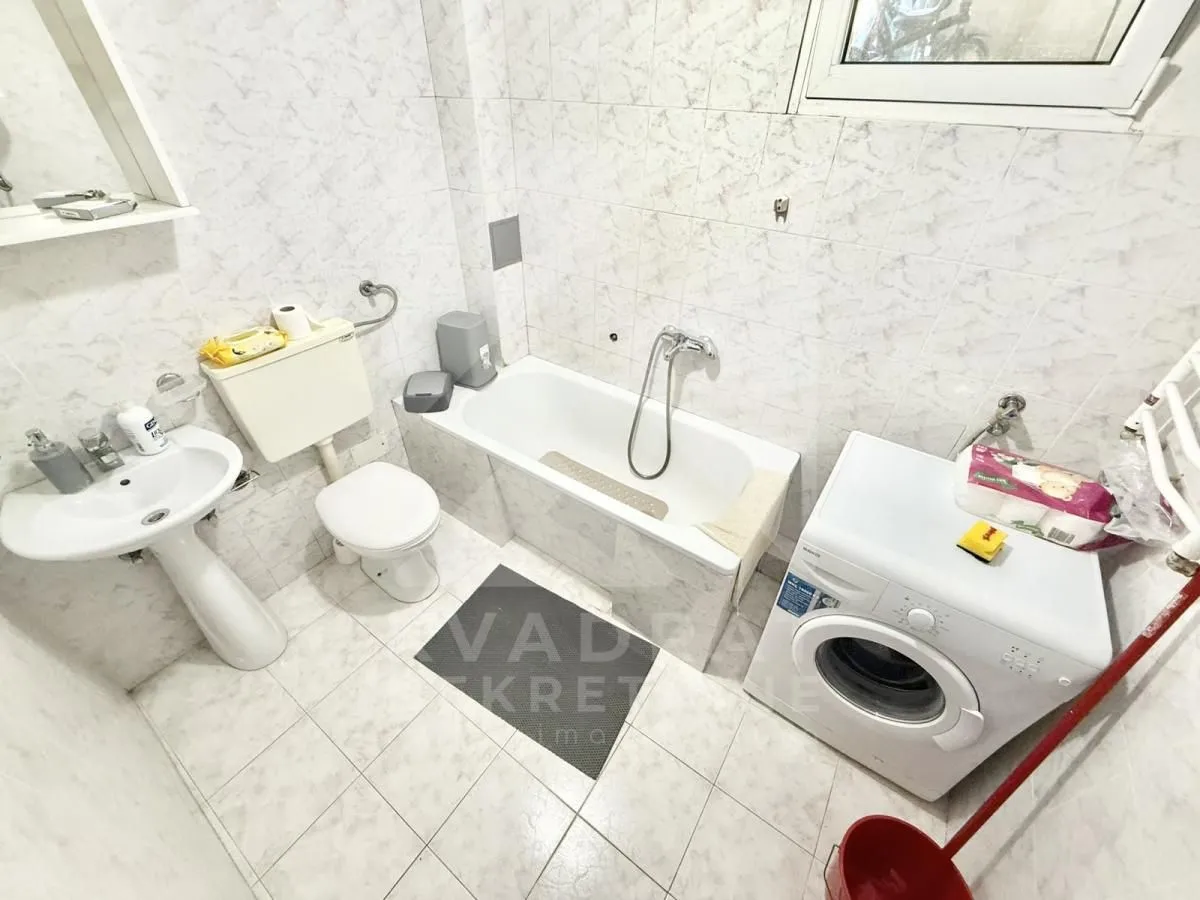 Smaller bathroom with a bathtub, washbasin, toilet, and washing machine.