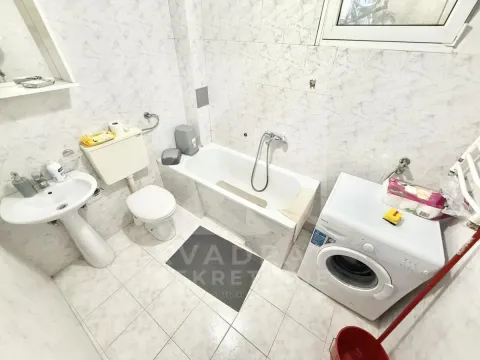 Smaller bathroom with a bathtub, washbasin, toilet, and washing machine. - image 5