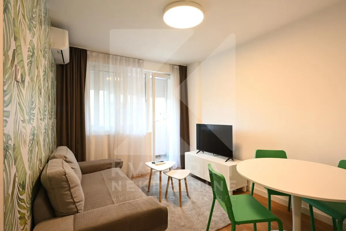 Living room with sofa, TV and dining table.