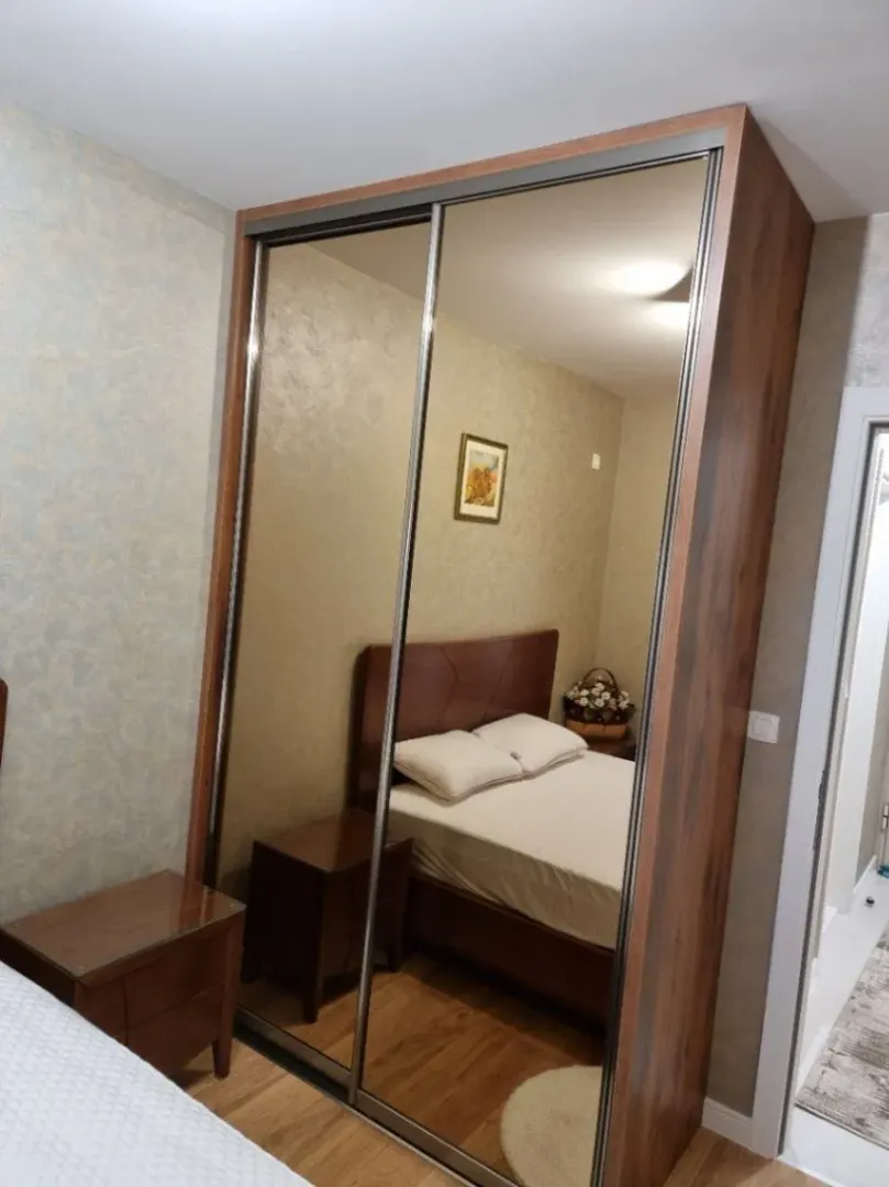 Bright bedroom featuring a mirrored wardrobe and a bed.