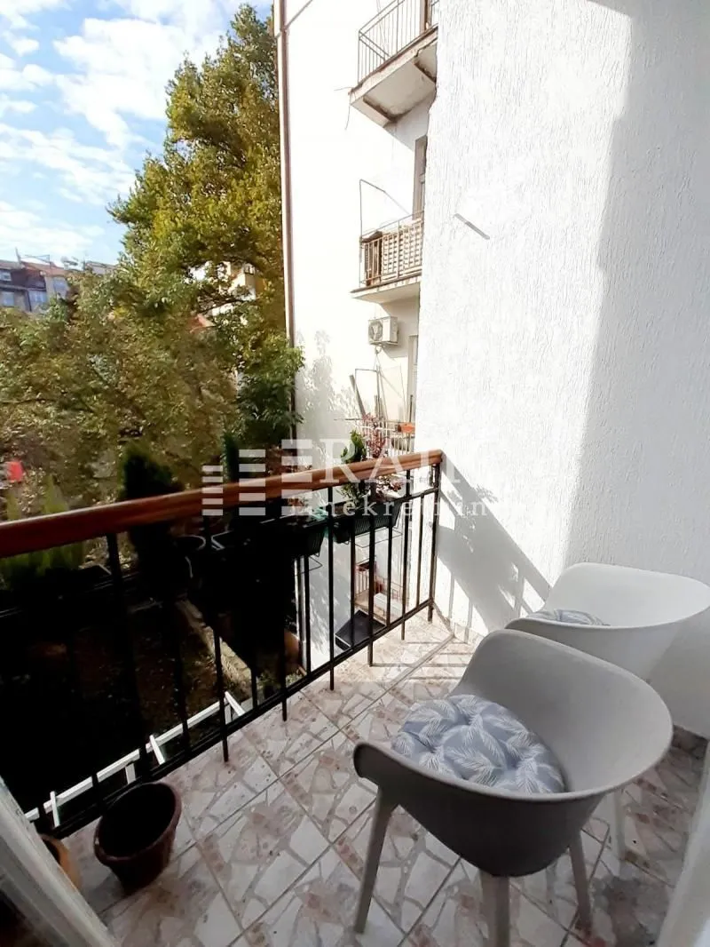 Small furnished balcony with two chairs and a view of greenery.