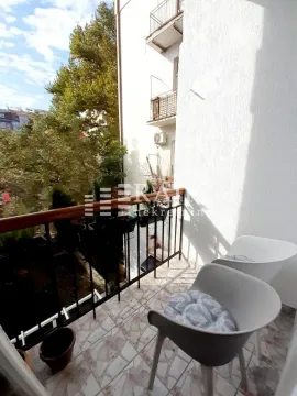 Small furnished balcony with two chairs and a view of greenery. - image 12
