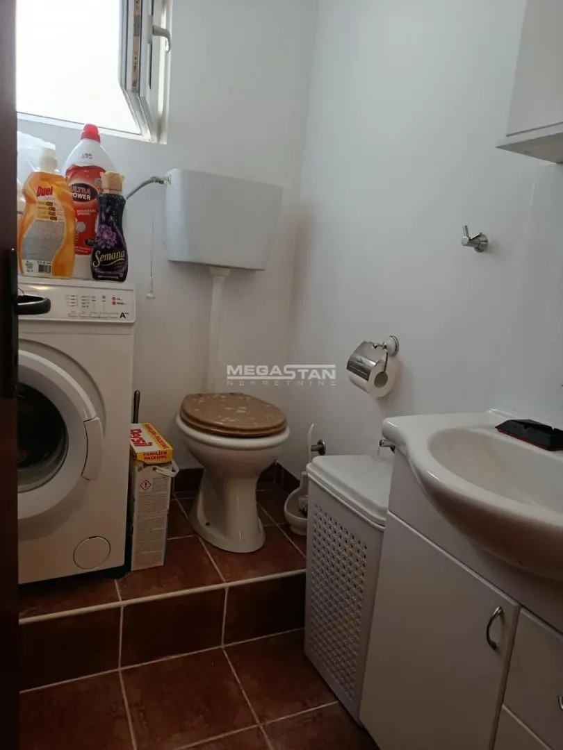 Small bathroom with toilet, washbasin and washing machine.
