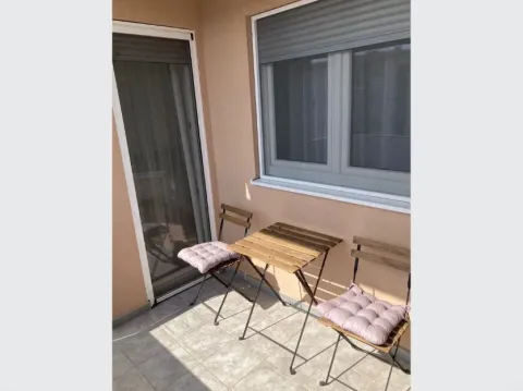 Small covered balcony with a wooden table and two chairs. - image 8