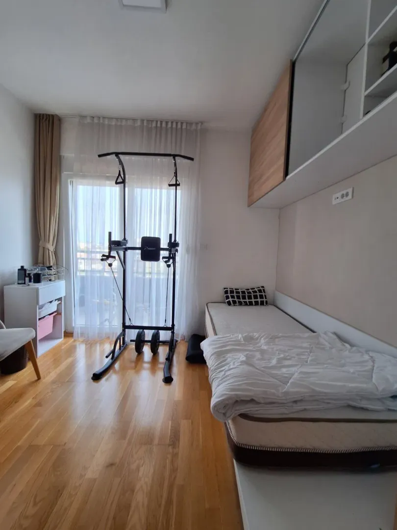 Spavaća soba sa krevetom, ugradnim ormarom i spravom za vježbanje.