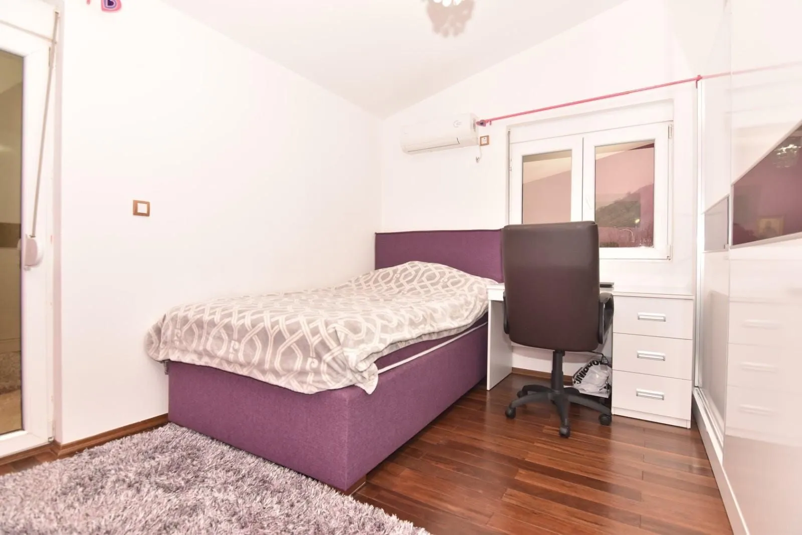 Small bedroom with a bed, desk, and white wardrobe.