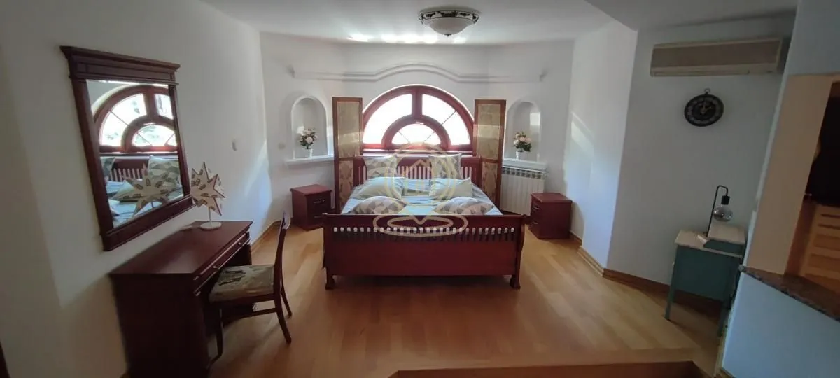 Spacious bedroom with a double bed, wooden furniture, and a desk.