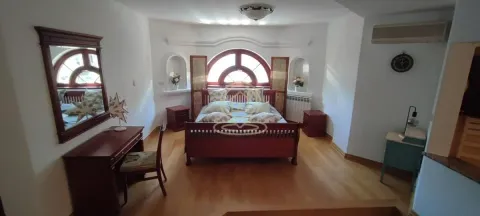 Spacious bedroom with a double bed, wooden furniture, and a desk. - image 12