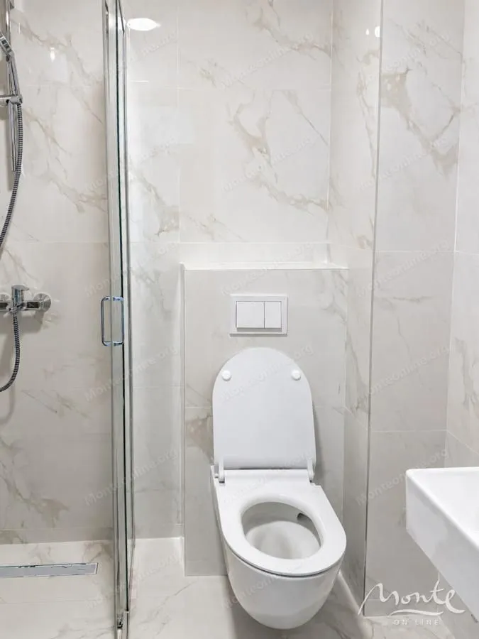 Moderno opremljeno kupatilo sa tuš kabinom i bijelim sanitarijama.