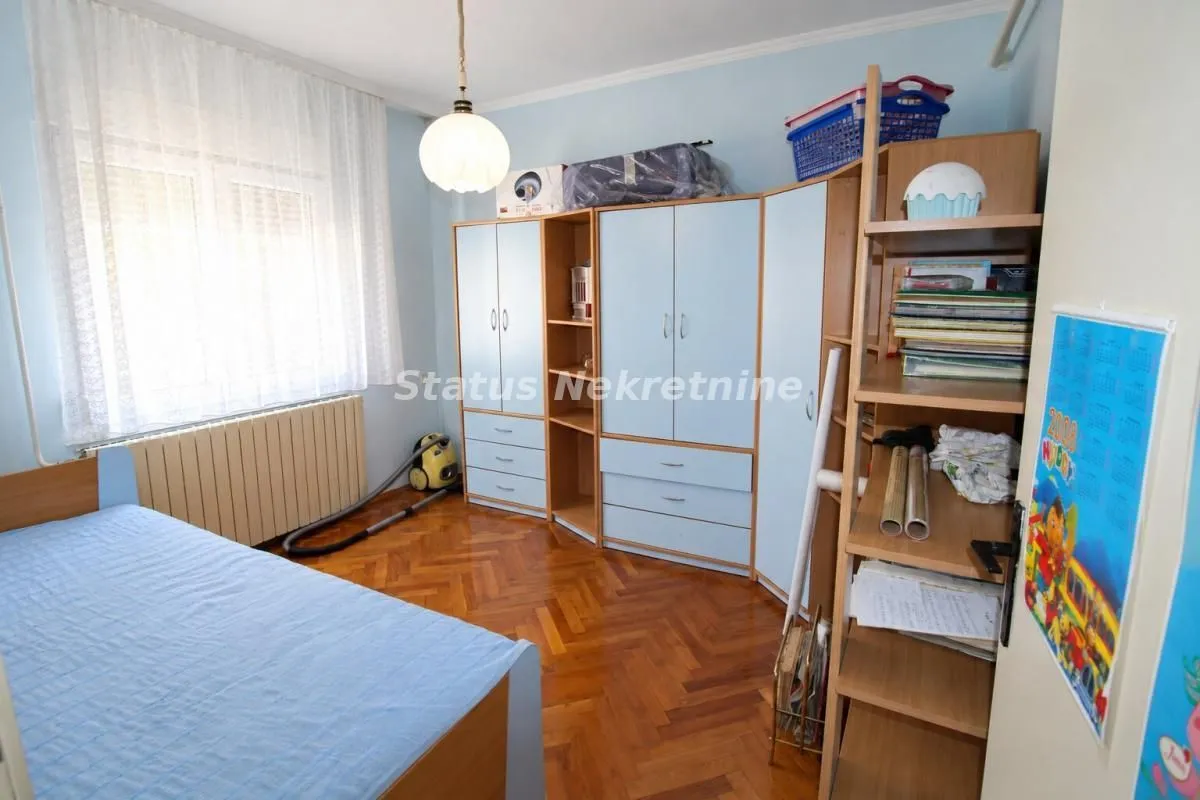 Nameštena spavaća soba sa krevetom, garderoberom i drvenim podom.