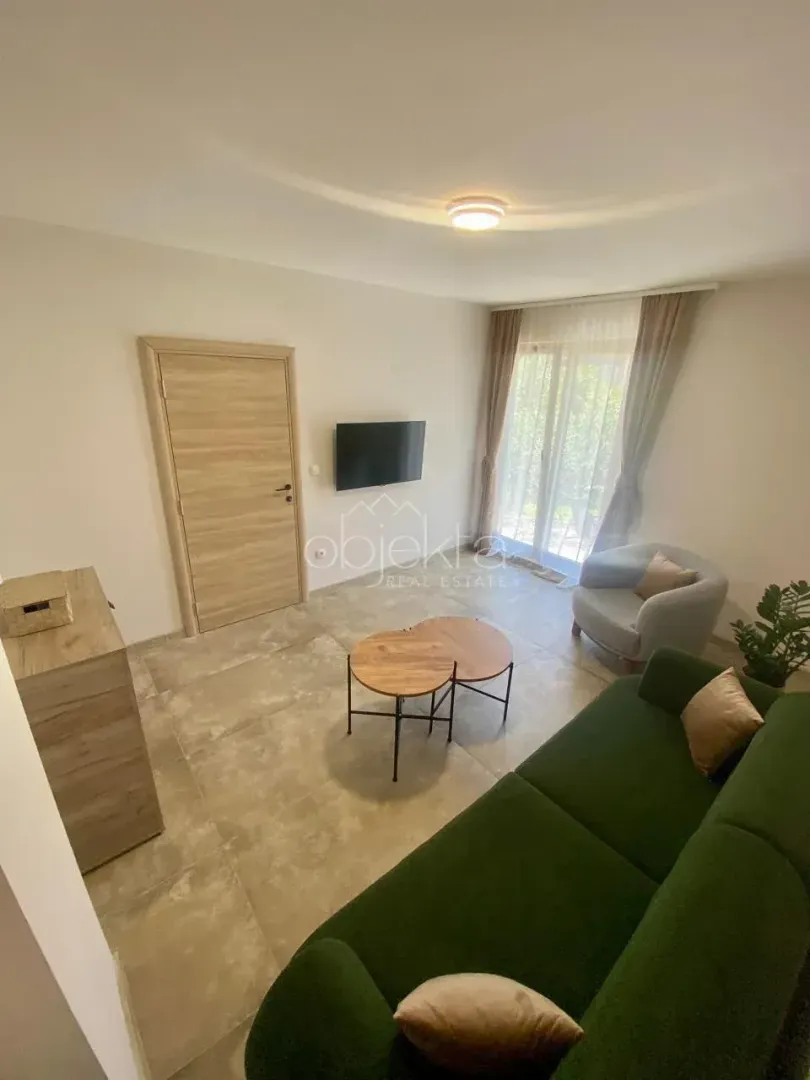 Living room with a green sofa, coffee tables, and a wall-mounted TV.