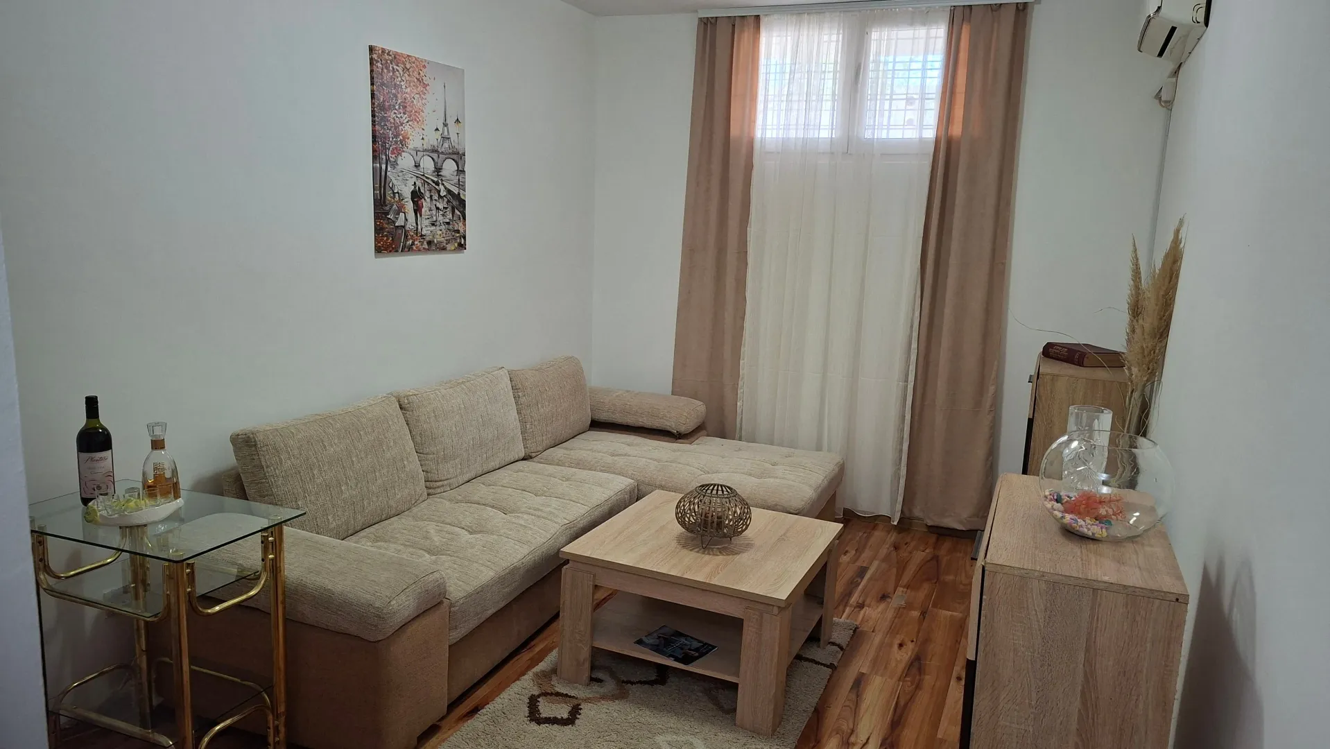 Living room with a sectional sofa, a wooden coffee table, and a window with curtains.