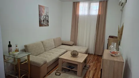 Living room with a sectional sofa, a wooden coffee table, and a window with curtains. - image 10