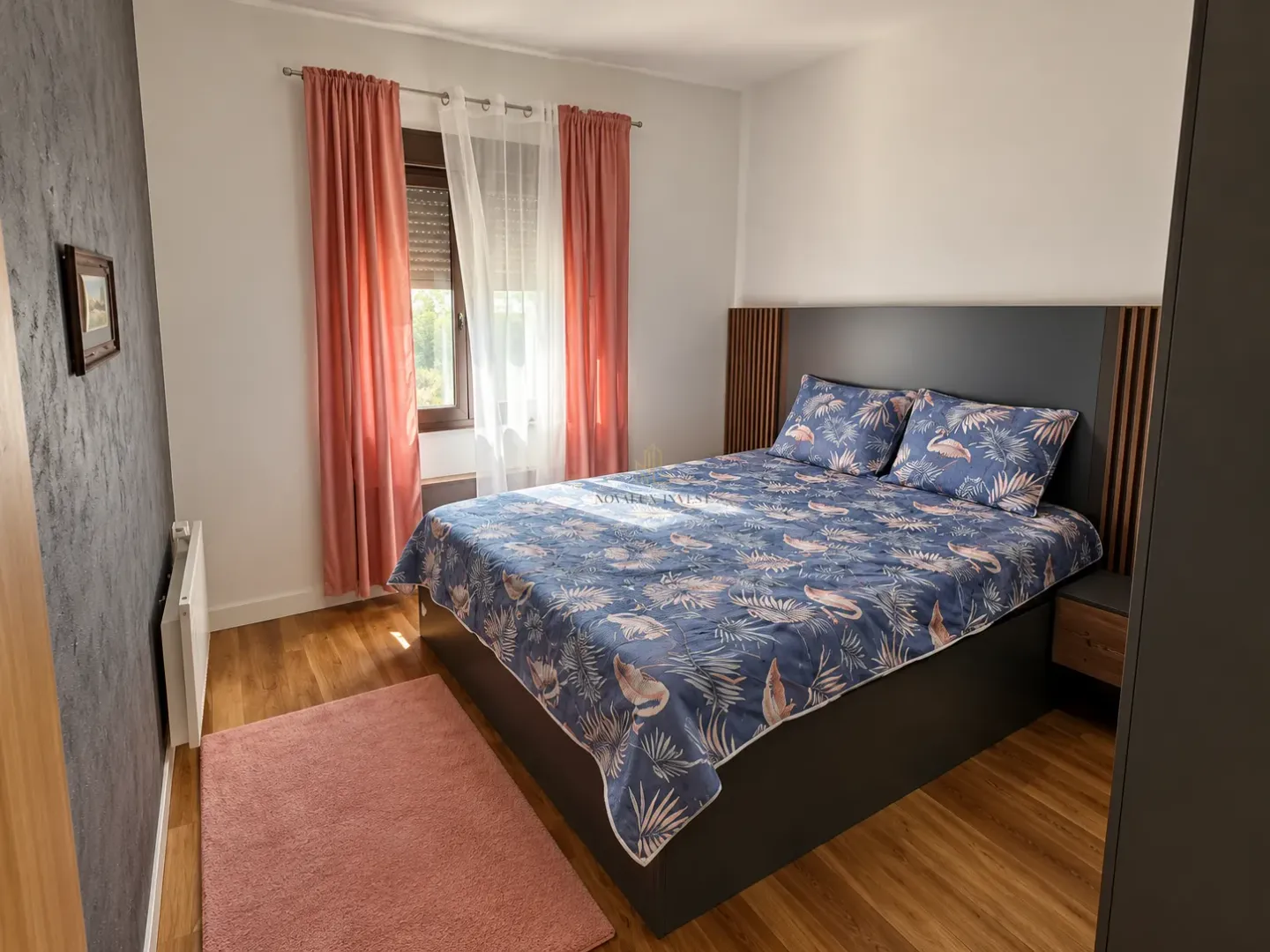 Furnished bedroom with a double bed, window, and pink curtains.