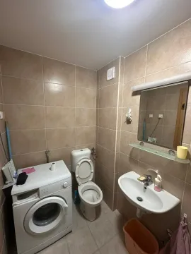 Small bathroom with a sink, toilet, and washing machine tiled with ceramic tiles. - image 3