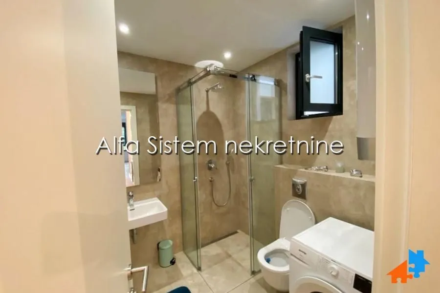 Bathroom equipped with a shower cabin, washbasin, toilet, and washing machine.