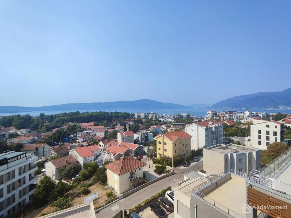 Pogled sa terase na naselje, more i planine u daljini.