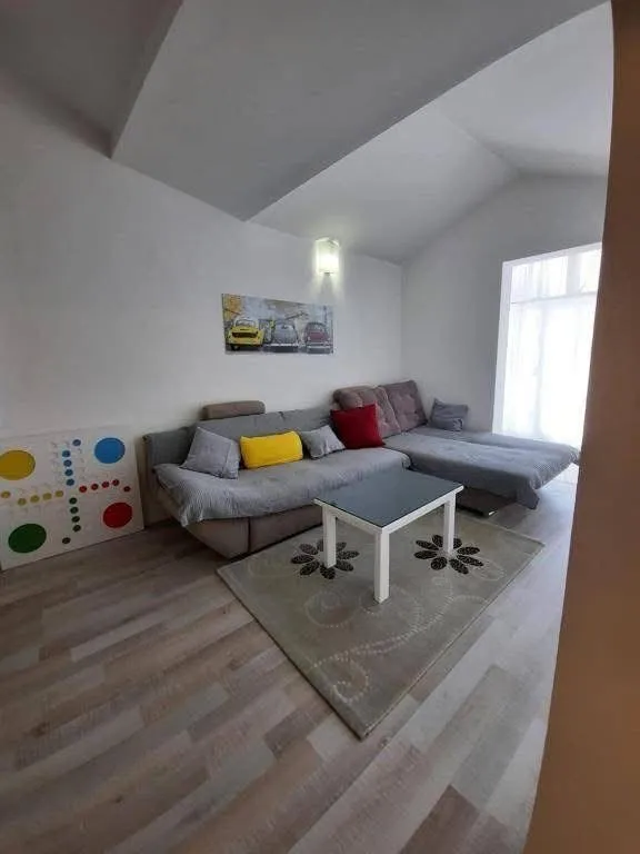 Dnevna soba sa ugaonom garniturom, stočićem i tepihom.