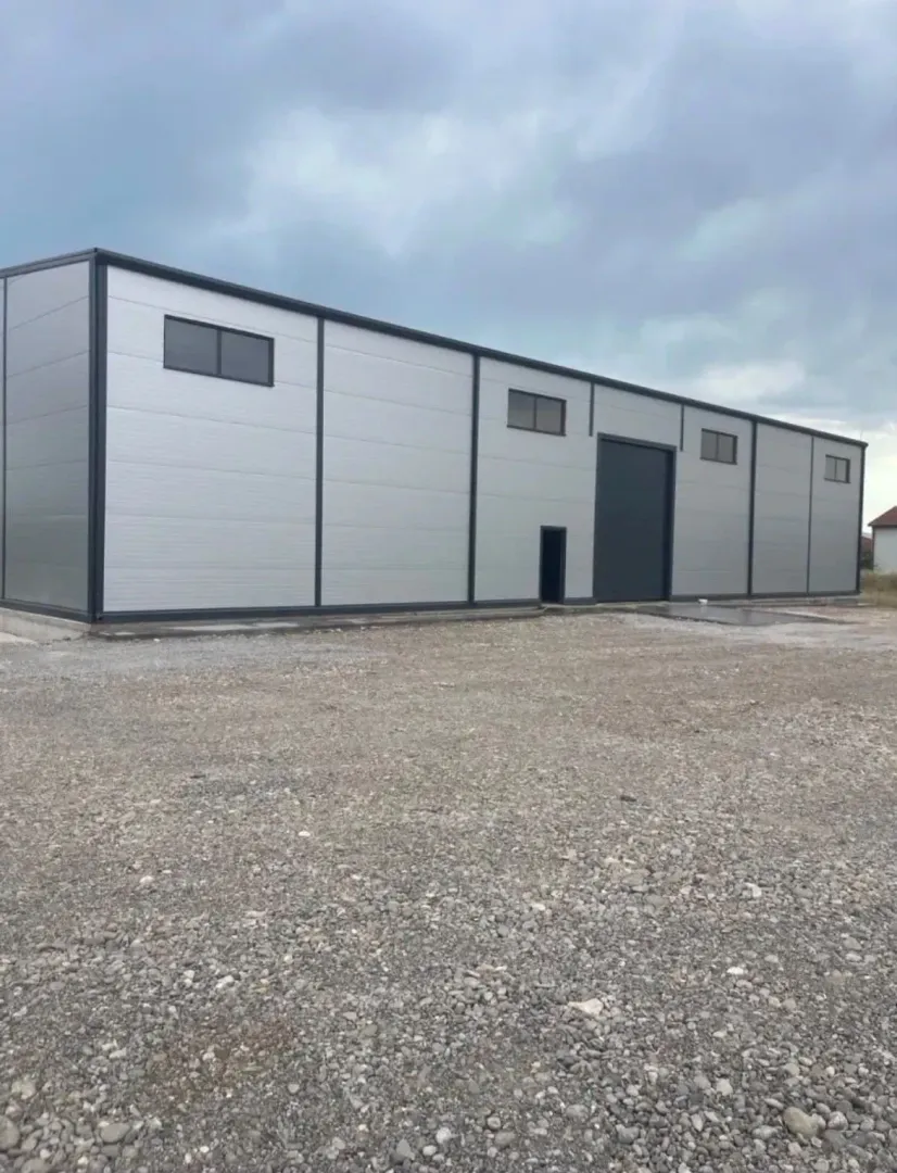 View of the exterior of an industrial building with a metal facade and a gravel courtyard.