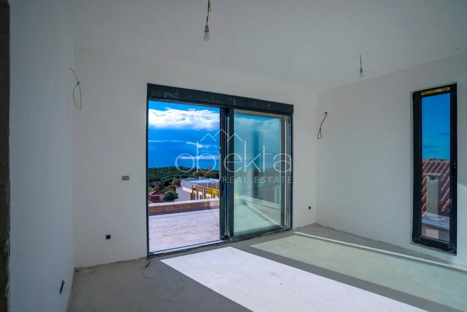 View from an unfurnished room with access to the terrace and a sea view.