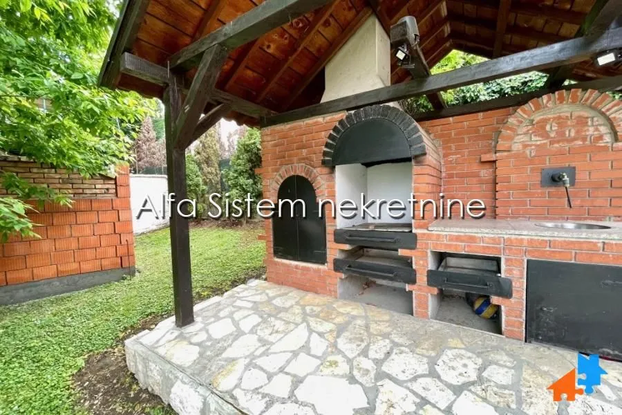 Covered backyard area with a brick barbecue and stone flooring.