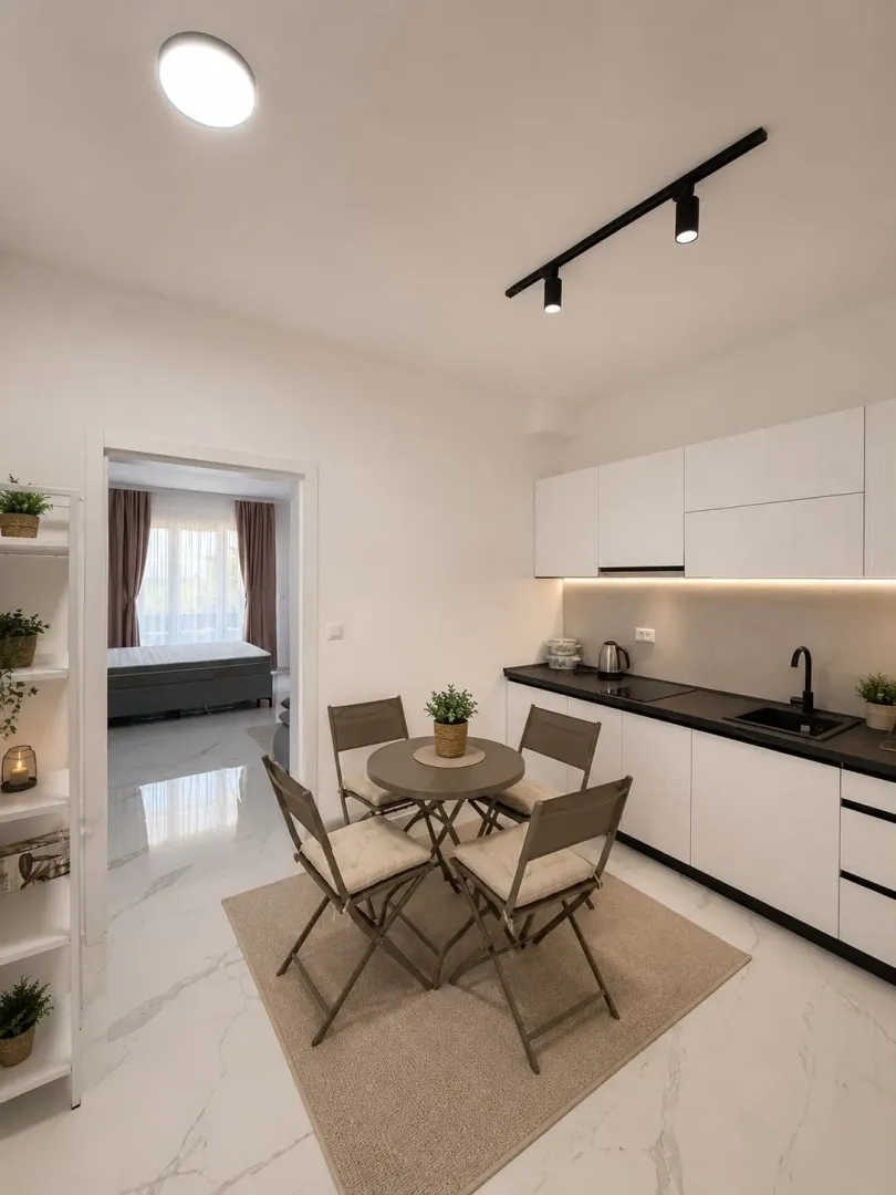 Modern kitchen with a dining table and a view into the bedroom.