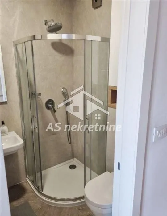 Pogled na kupatilo sa tuš kabinom i sanitarijama.