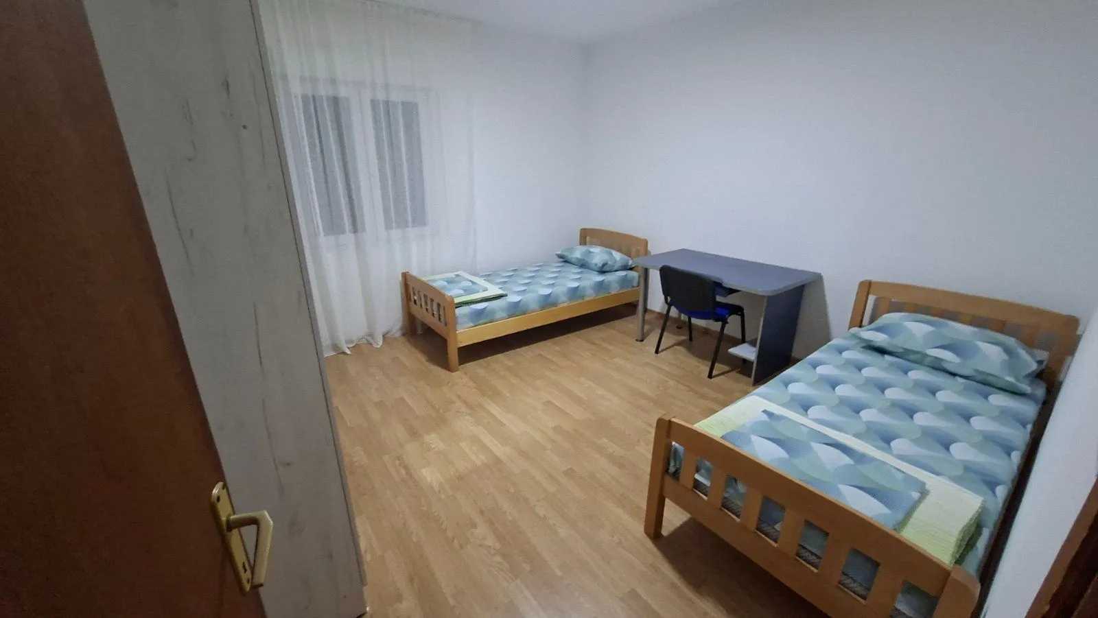 Spavaća soba sa dva kreveta i radnim stolom.