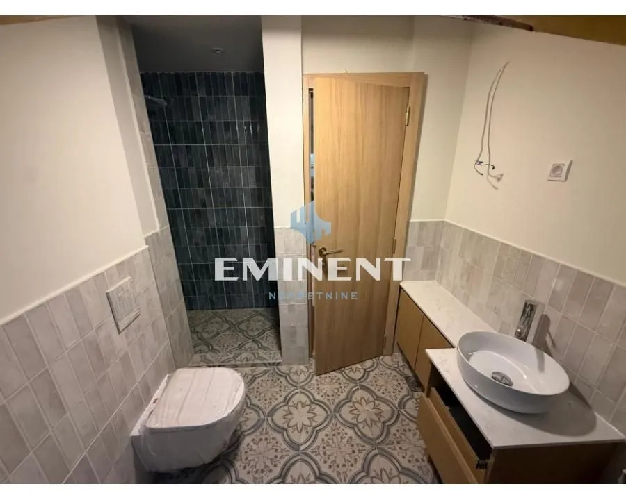 View of the new bathroom with a washbasin, toilet, and walk-in shower.