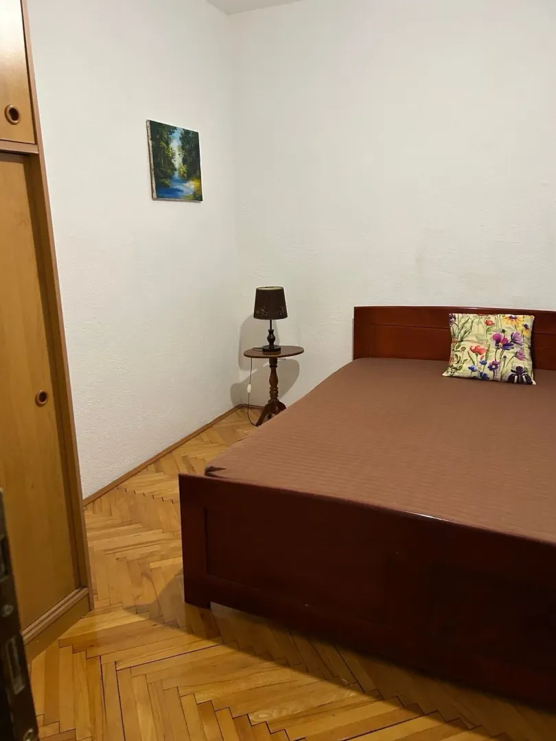 Furnished bedroom with a double bed, wardrobe, and parquet flooring.