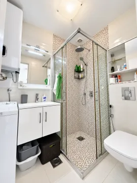 Small bathroom with a shower cabin, vanity, and wall-hung toilet. - image 7