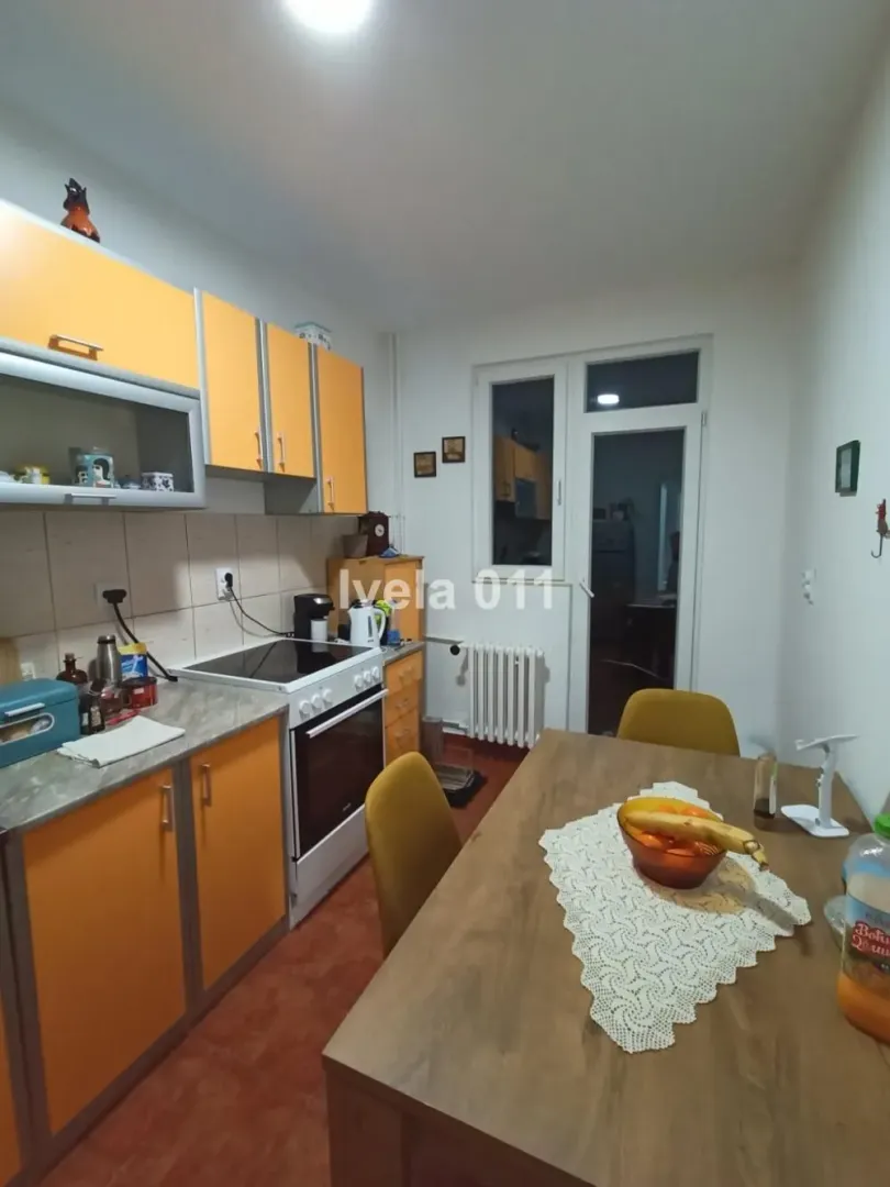 Kuhinja sa narandžastim elementima i trpezarijskim stolom.