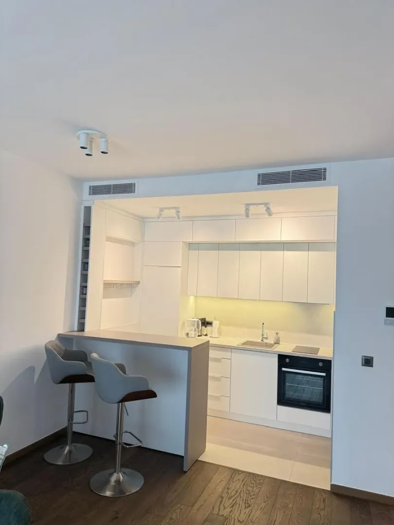 Modern white kitchen with a breakfast bar and bar stools.