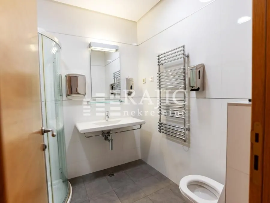 Modern bathroom with a shower cabin, washbasin, and toilet.