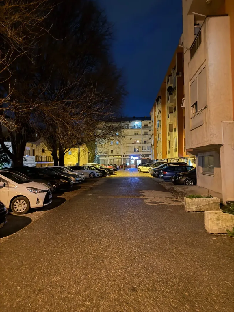 Noćni pogled na parking ispred stambene zgrade.