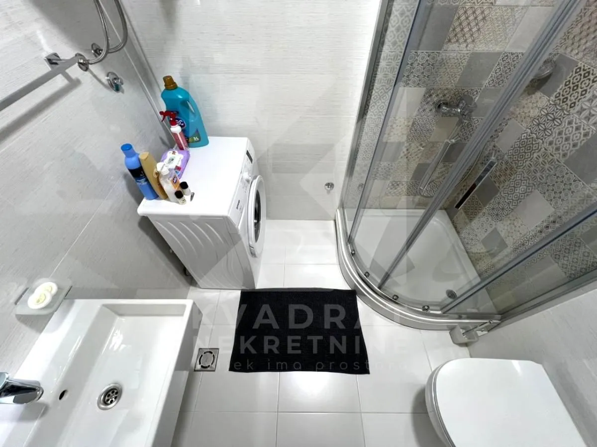 Bathroom equipped with a shower cabin, washbasin, toilet, and washing machine.
