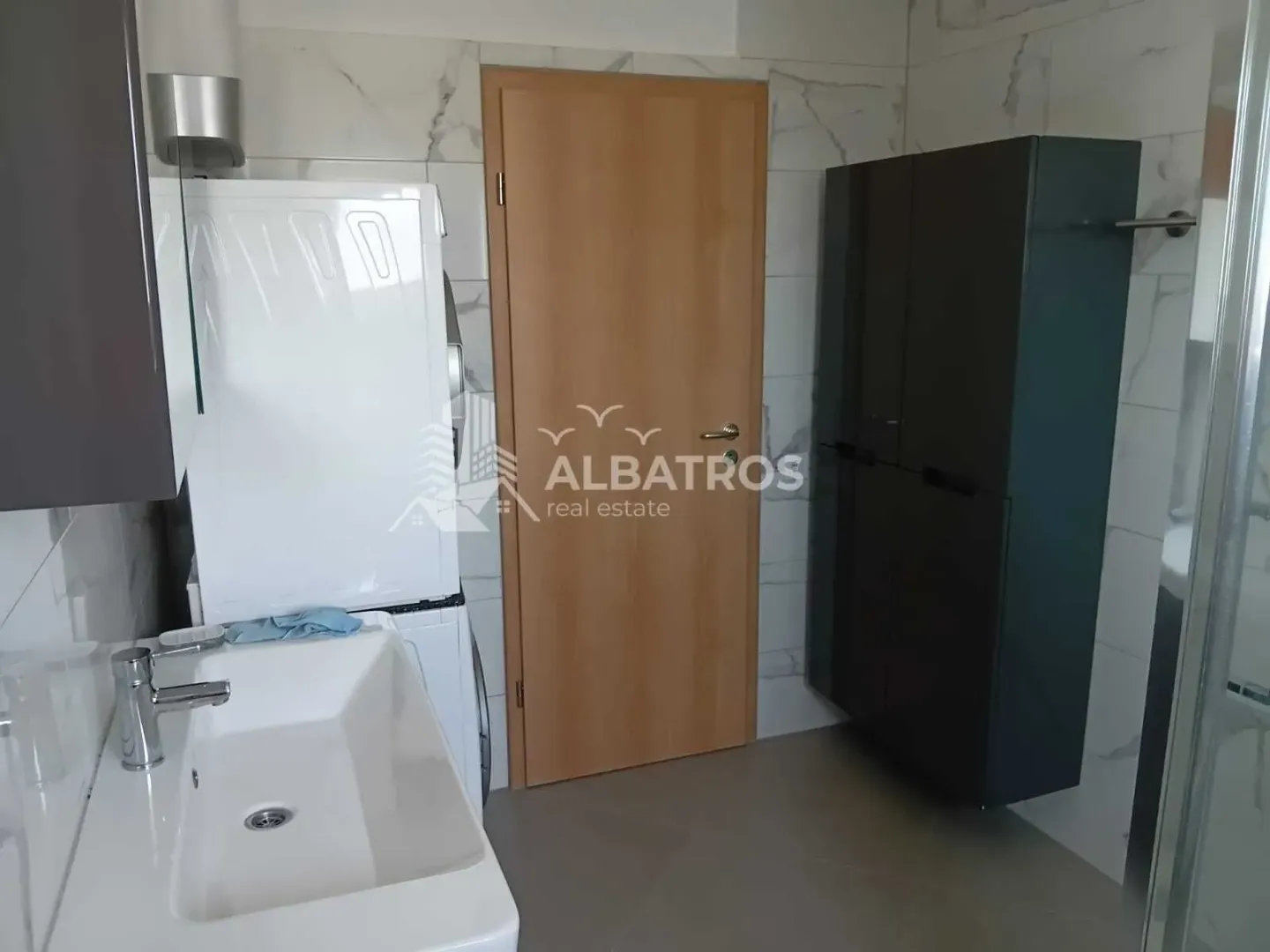 Bathroom with a washbasin, washing machine, and wooden door.