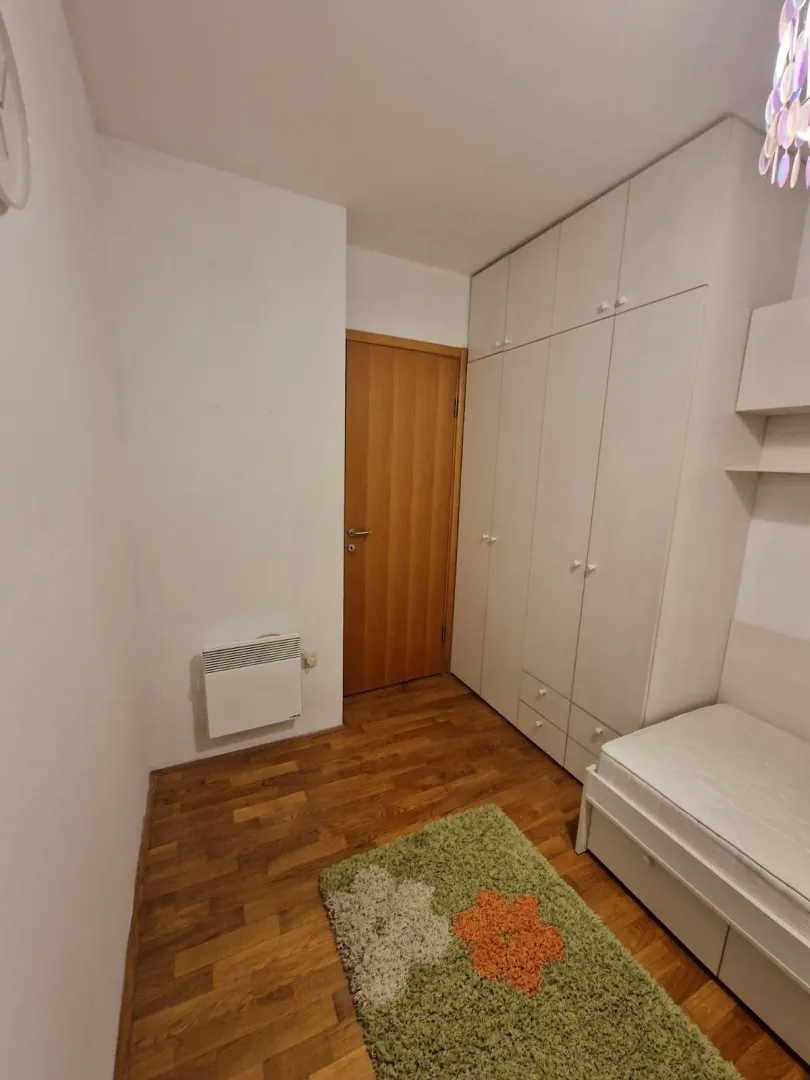 Mala spavaća soba sa jednim krevetom i velikim ugradnim ormarom.