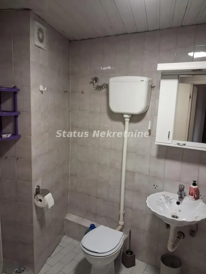 Manje kupatilo obloženo keramičkim pločicama sa toaletom i umivaonikom.